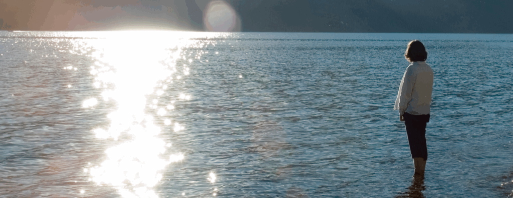 yoga participant standing in lake water in mountain pose