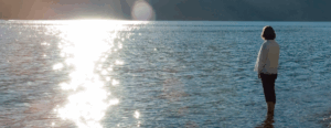 yoga participant standing in lake water in mountain pose